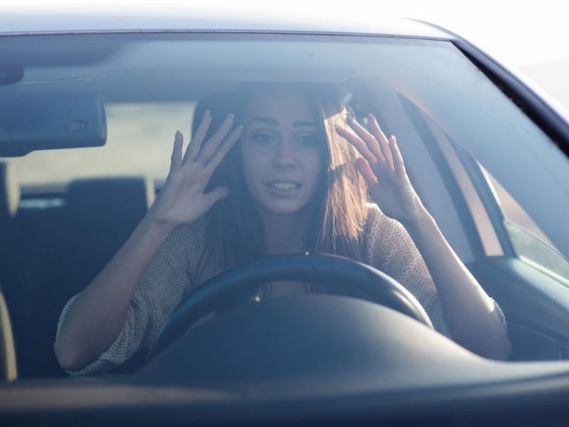 Young woman sitting scared in car